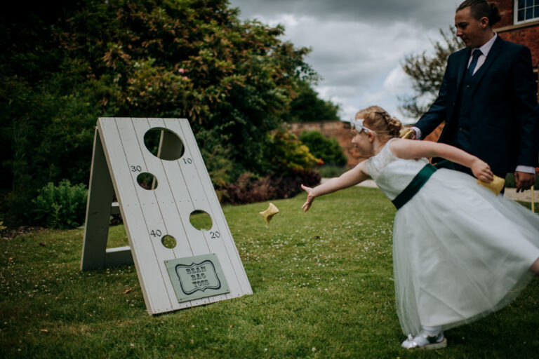 A girl playing bean bag toss | garden game available to hire from Emma Lane Designs