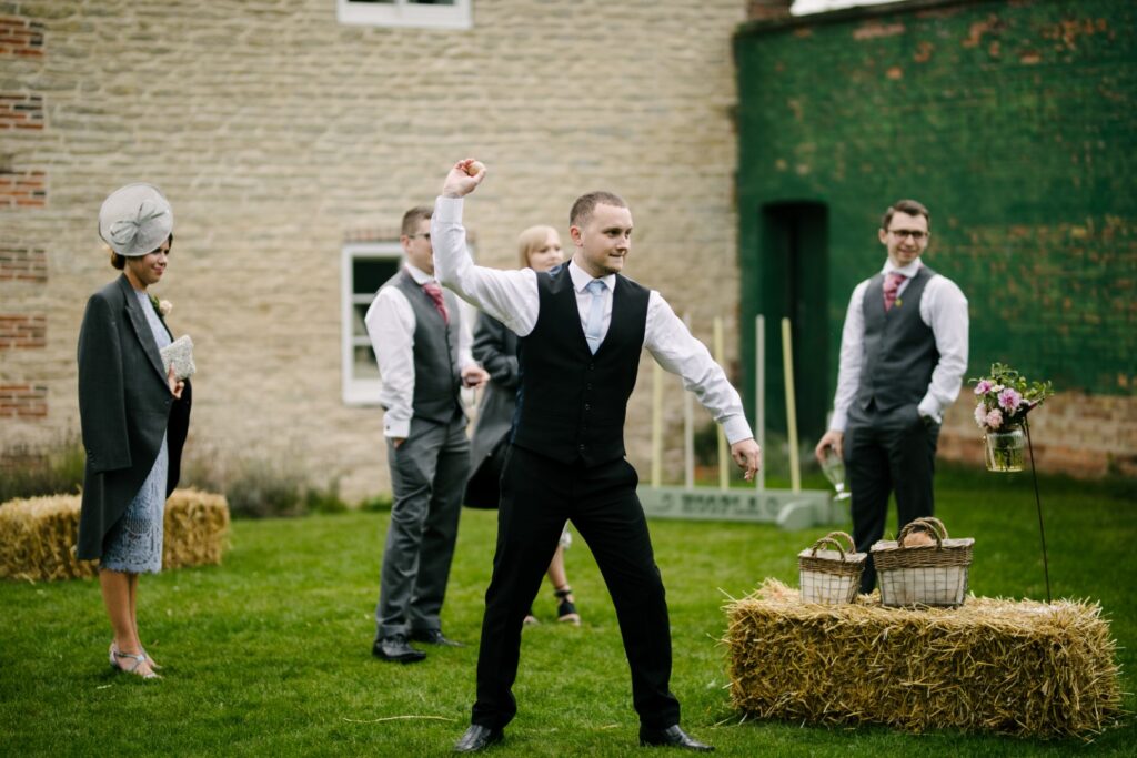 Wedding guests playing a traditional game of Coconut Shy at Cleatham Hall in Lincolnshire | Luxury Coconut Shy Garden Game Hire