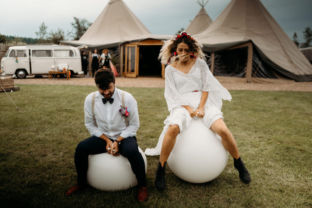 A bride and Groom bouncing on adult sized white space hoppers at their wedding at Inkersall Grange Farm | Giant White Space Hoppers garden games hire in Derbyshire, Nottinghamshire and Lincolnshire