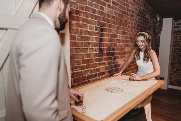 Bride and groom playing a game of Shuffle puck, a luxury indoor game hire for weddings and events UK