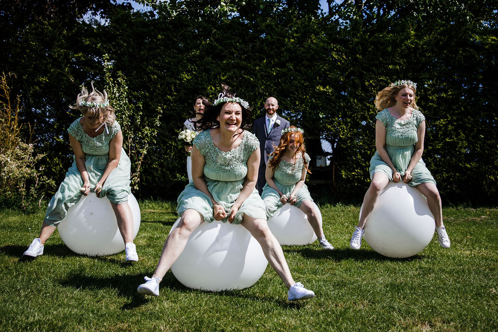 Bridesmaids having a space hopper race on white adult sized space hoppers hired from Emma Lane Designs - luxury garden games for weddings