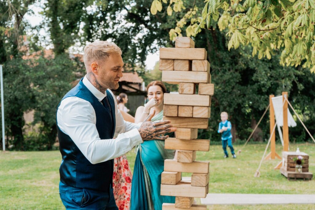 An intense game of giant jenga being played on the grassed area. Giant Jenga garden games hire