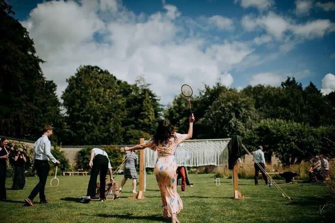 Guests at a wedding playing badminton with a macrame badminton net. A luxury garden games hire for weddings from Emma Lane Designs