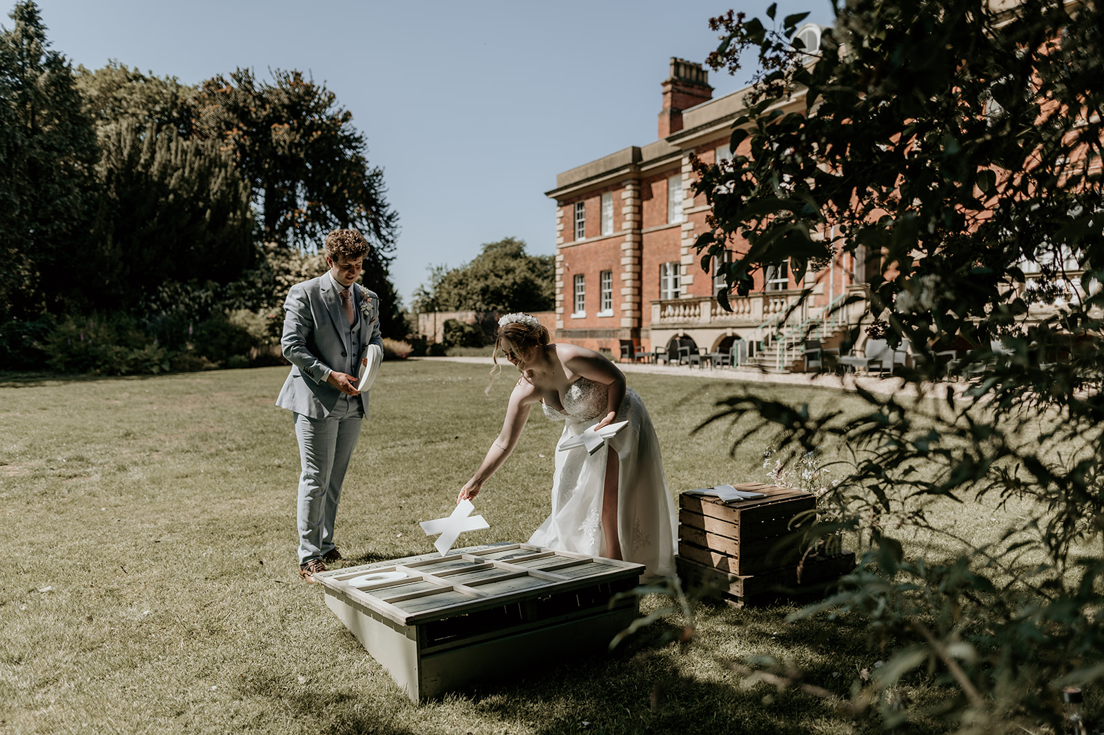 Bride and Groom playing a game of Noughts and Crosses on the lawn at Hirst Priory in Crowle, Lincolnshire. The game is aluxury garden game for weddings for hire from Emma Lane Designs
