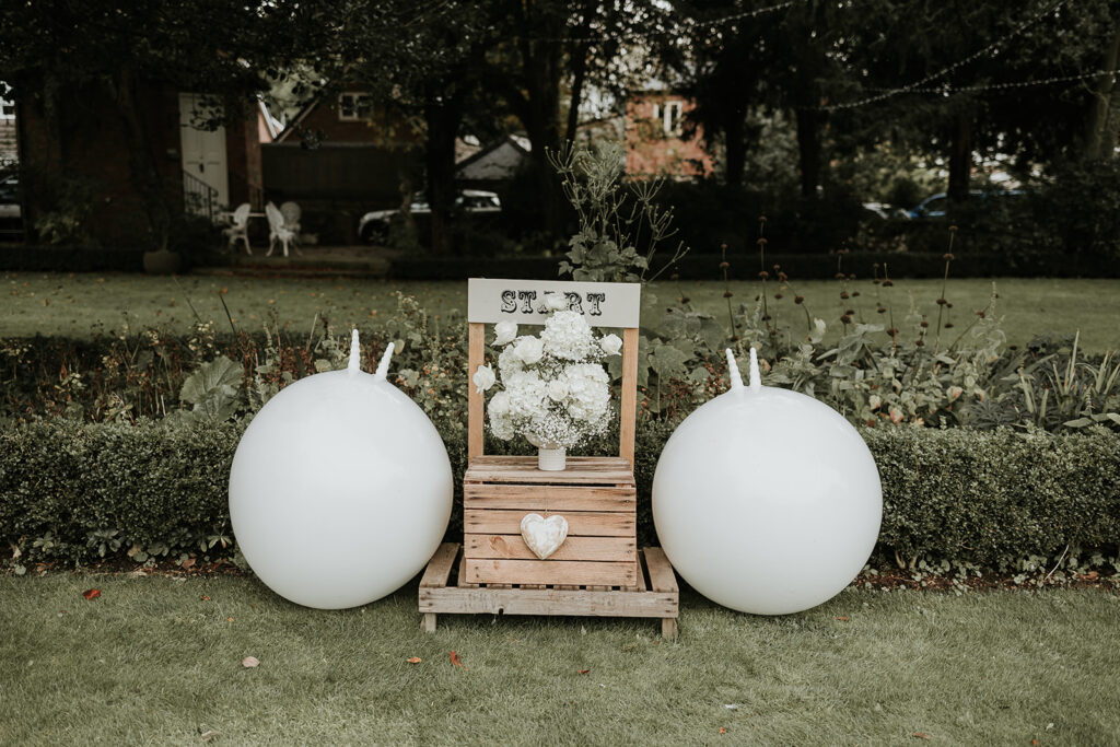 Large adult sized white space hoppers with a start sign in the middle and a white floral arrangement.