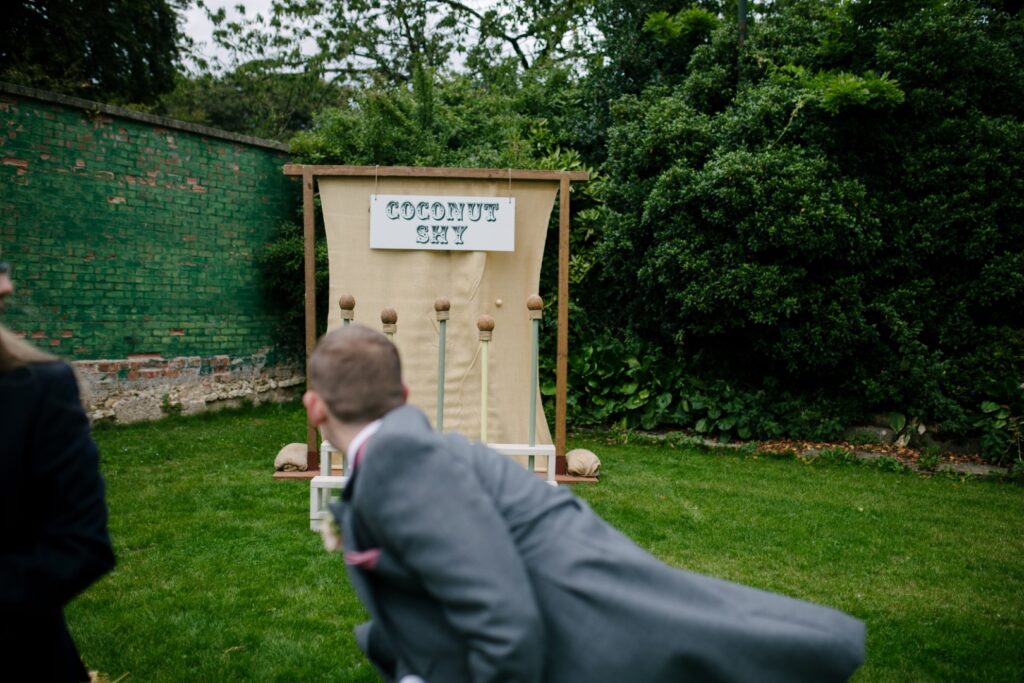 Playing coconut shy on the lawn. Luxury garden games hire for weddings and events