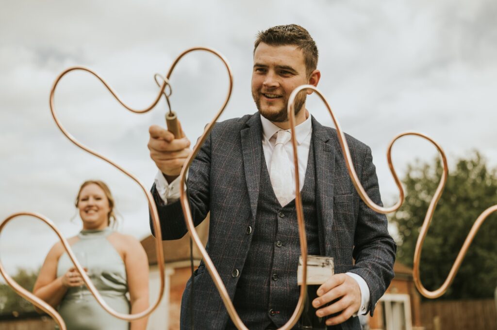 A guy is playing buzz wire, a game from Emma Lane Designs Garden and Indoor Games Hire for weddings and events