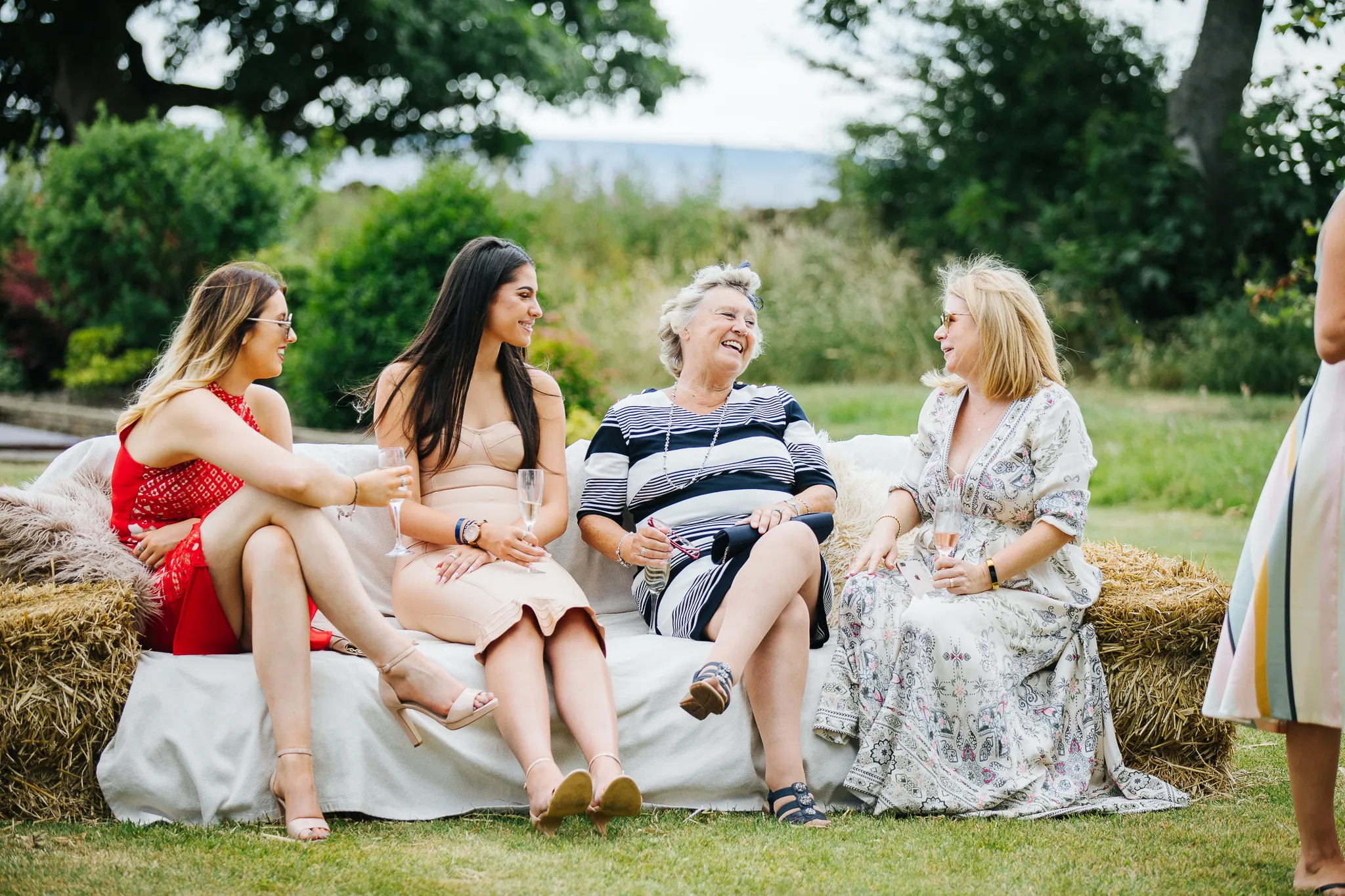 Wedding guests relaxing and having fun on a bale sofa.