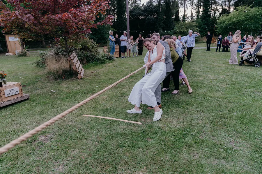 Bride and wedding guests playing a game of Tug of War and having fun. 