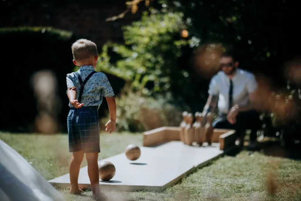 A young boy playing a game of skittles at a wedding