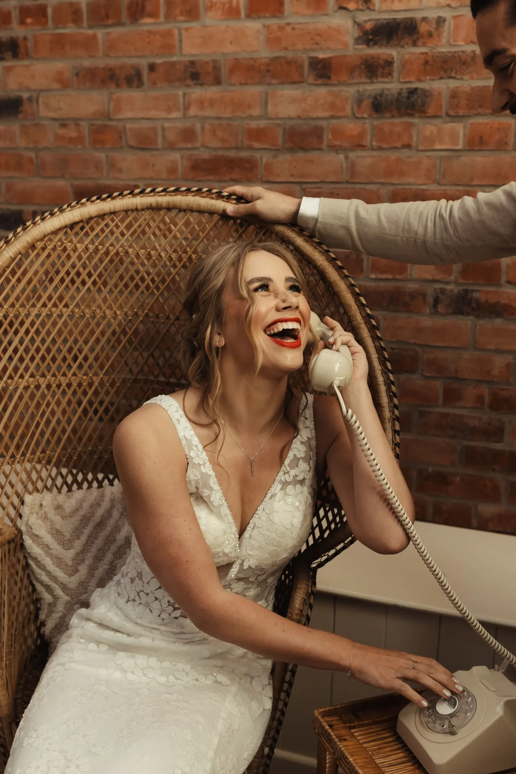 Bride laughing whilst leaving an audio guestbook message on an old style telephone. Fun for every wedding