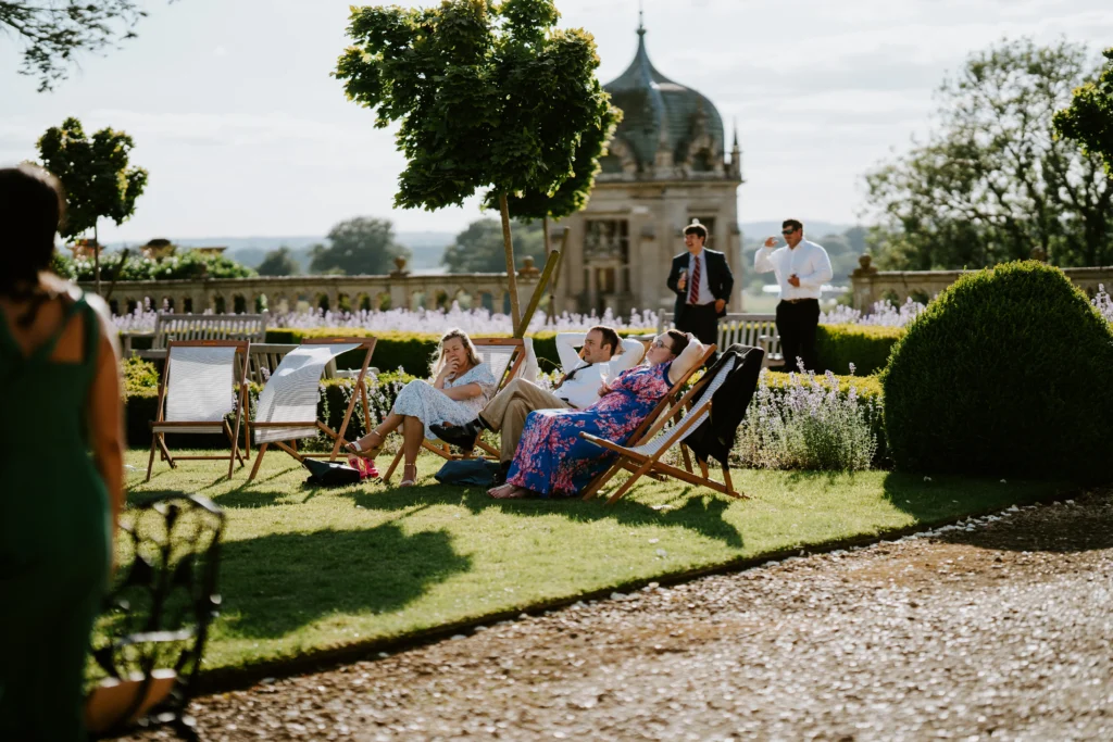 Wedding guests relaxing in deckchairs watching others playing garden games.